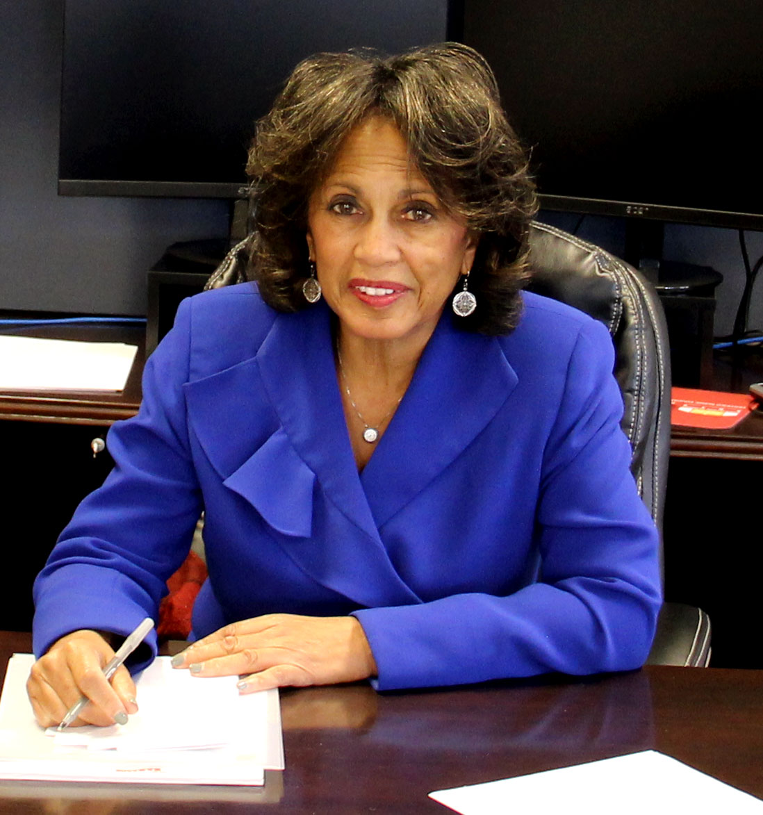 Dr. Beverly Malone smiling at a desk while writing on a notepad