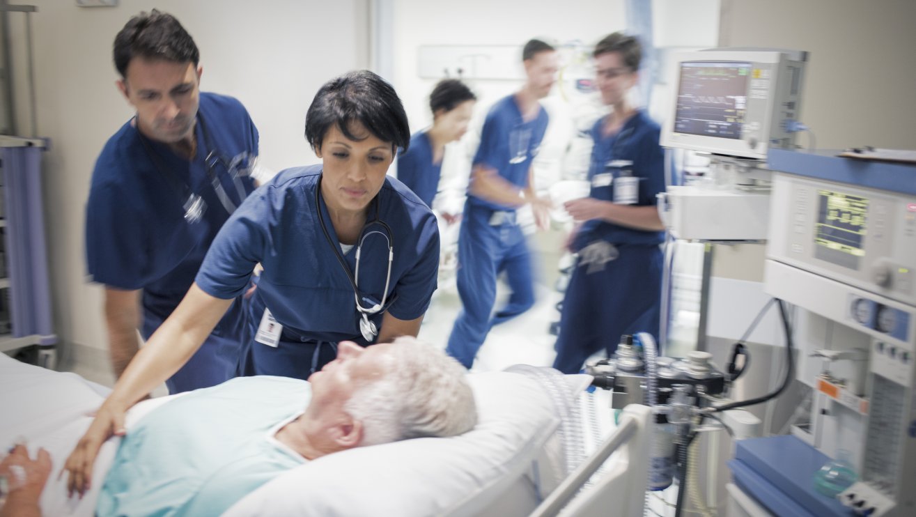 Two doctors preparing elderly patient before medical procedure.