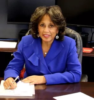 Dr. Beverly Malone Dr. Beverly Malone smiling at a desk while writing on a notepad